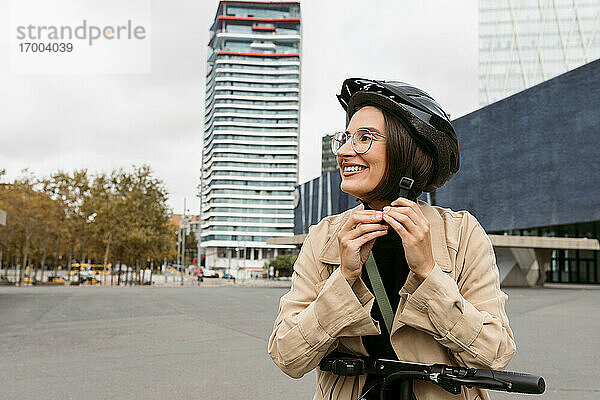 Lächelnde Frau mit Fahrradhelm auf der Straße in der Stadt