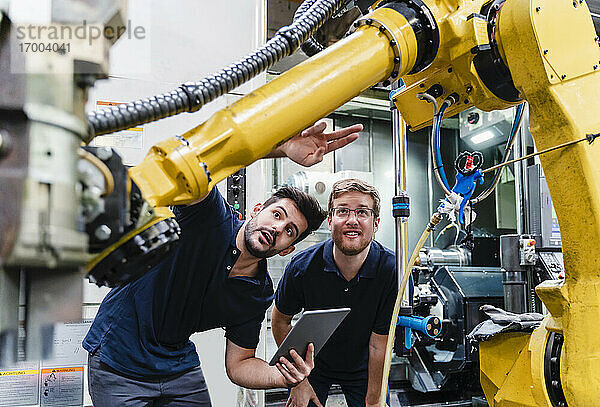 Männliche Mitarbeiter bei der Untersuchung eines Roboterarms in der Fertigungsindustrie