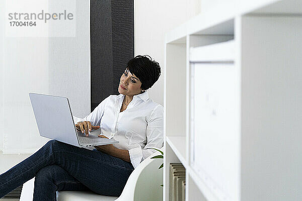 Geschäftsfrau in Bürosessel mit Laptop sitzend