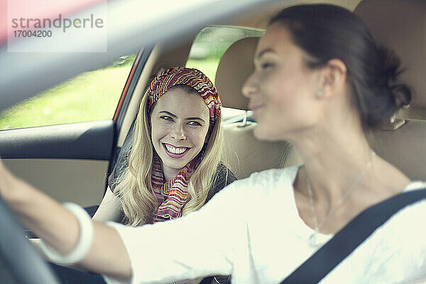 Lächelnde Freunde  die sich im Auto auf einer Autoreise unterhalten