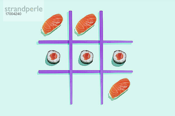 Tic-Tac-Toe-Spiel mit Lachs-Sushi-Maki und Nigiri mit lila Stäbchen auf mintgrünem Hintergrund