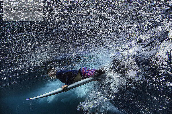Männlicher Surfer mit Surfbrett auf einer Unterwasserwelle