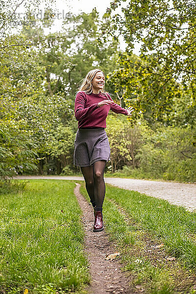 Fröhliche Frau läuft im Herbst im Park