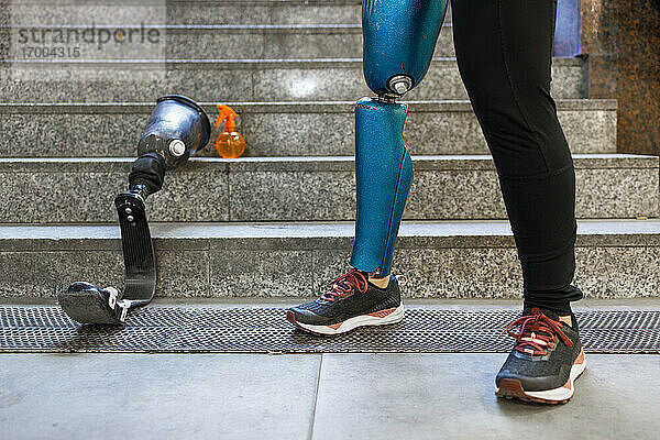 Junge Sportlerin mit Beinprothese steht mit Prothese auf einer Treppe