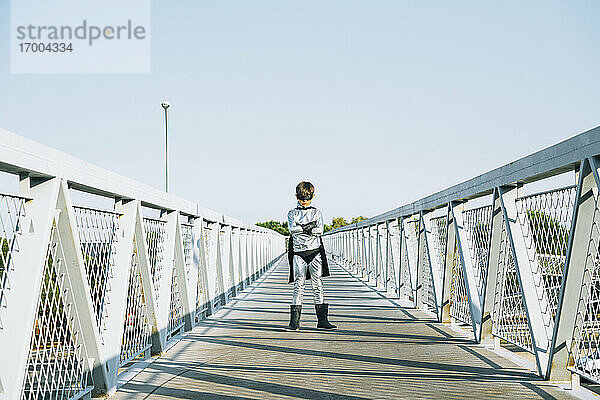 Porträt eines als Superheld verkleideten Jungen  der auf einer Fußgängerbrücke steht