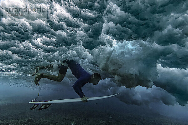 Männlicher Surfer mit Surfbrett unter Wasser im Urlaub auf den Malediven