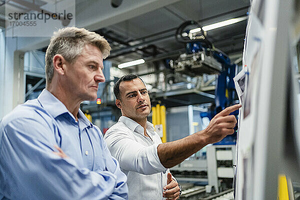Ein männlicher Unternehmer erklärt seinem Vorgesetzten während einer Besprechung in einer Fabrik die Geschäftsstrategie