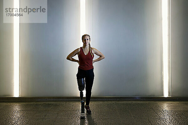 Selbstbewusste Sportlerin mit Beinprothese steht auf dem Fußweg in einer Unterführung