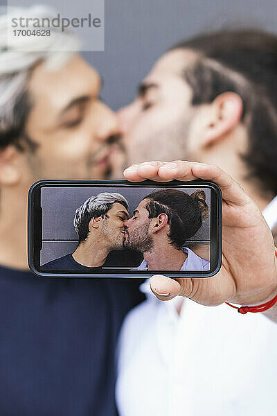 Mann fotografiert beim Küssen eines schwulen Partners in der Stadt