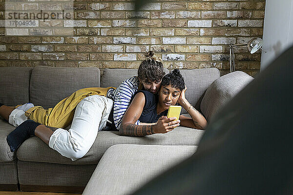 Frau  die ihre Freundin umarmt und ein Selfie mit dem Handy macht  während sie sich zu Hause entspannt