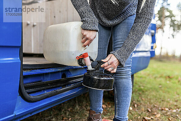 Mittlere erwachsene Frau gießt Wasser in eine Camping-Teekanne