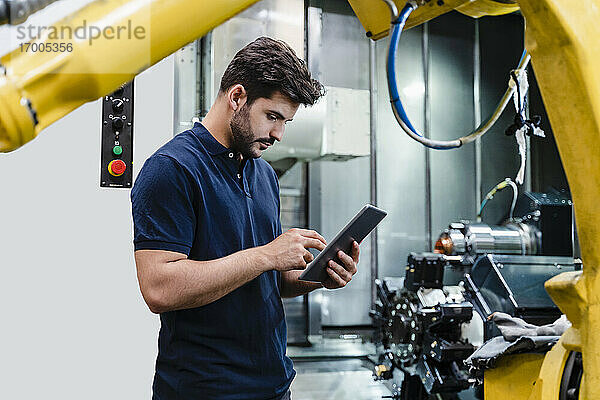 Männlicher Arbeiter  der ein digitales Tablet benutzt  während er in einer Fabrik steht