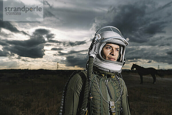 Mann posiert als Astronaut gekleidet mit dramatischen Wolken im Hintergrund