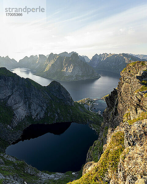 Wanderin bewundert die Aussicht  während sie auf einem Berg bei Reinebringen  Lofoten  Norwegen  steht