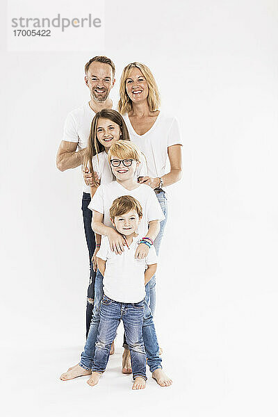 Glückliche Familie mit Kindern in einer Reihe stehend vor weißem Hintergrund
