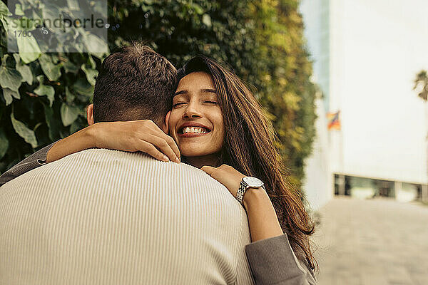 Lächelnde Freundin umarmt ihren Freund im Park