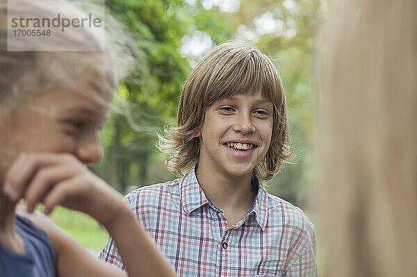Glücklicher Junge im Gespräch mit Freunden in einem öffentlichen Park
