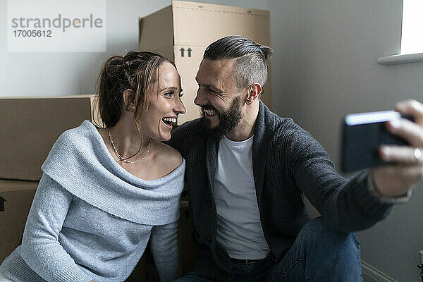 Fröhliches Paar  das sich beim Selfie in seinem neuen Zuhause von Angesicht zu Angesicht sieht