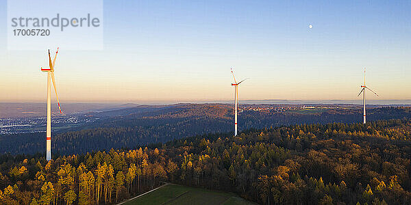 Windkraftanlagen im herbstlichen Wald in der Abenddämmerung