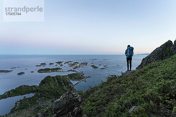 Wanderin bewundert den Sonnenuntergang auf dem Festvagtinden  Lofoten  Norwegen