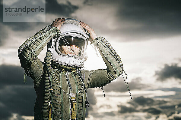 Mann posiert als Astronaut gekleidet mit dramatischen Wolken im Hintergrund