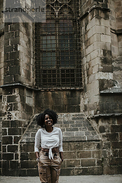 Lächelnde Frau mit Händen in den Taschen vor der Kathedrale von Barcelona  Barcelona  Spanien