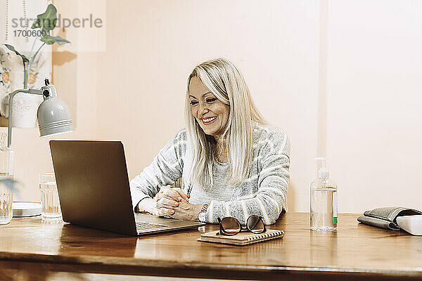 Glückliche Seniorin  die zu Hause eine Online-Beratung über ihren Laptop in Anspruch nimmt