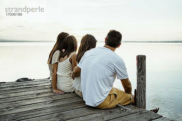 Familie bewundert den See  während sie am Steg sitzt