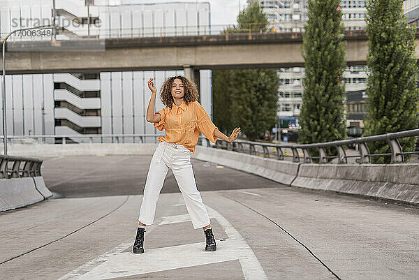 Unbekümmerte junge Frau tanzt auf einer Brücke in der Stadt