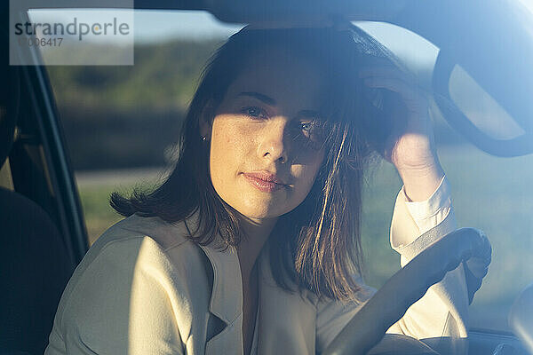 Nachdenkliche Frau im Auto auf einer Reise bei Sonnenuntergang