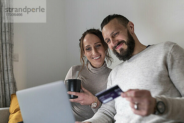 Lächelndes Paar beim Online-Shopping mit dem Laptop zu Hause