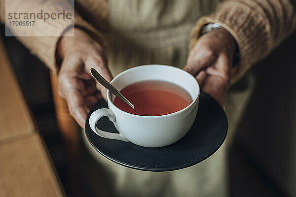 Ältere Frau hält eine Tasse Tee in den Händen