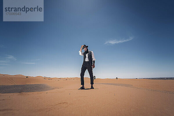 Mann mit Bart und Hut in den Dünen der Wüste von Marokko