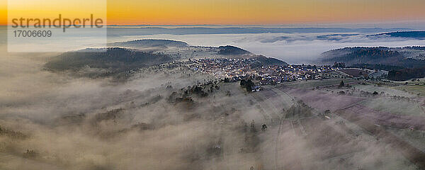 Deutschland  Baden-Württemberg  Berglen  Drohnenansicht eines in dichten Nebel gehüllten Dorfes in der Morgendämmerung