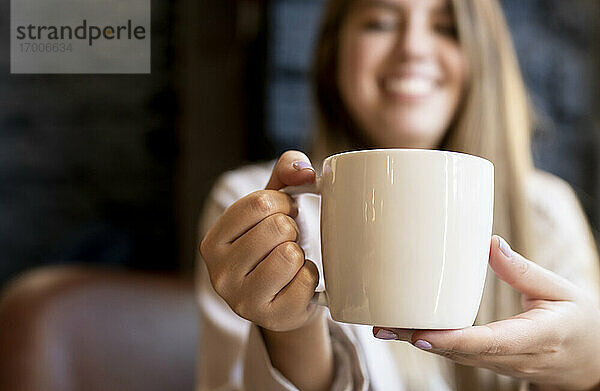 Frau hält Kaffeetasse  während sie in einem Cafe sitzt