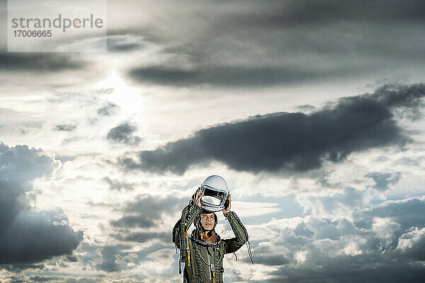 Mann posiert als Astronaut verkleidet auf einer Wiese mit dramatischen Wolken im Hintergrund