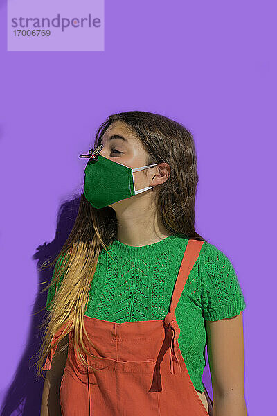 Teenager-Mädchen mit Gesichtsschutzmaske betrachtet Fliegenaufkleber auf der Nase