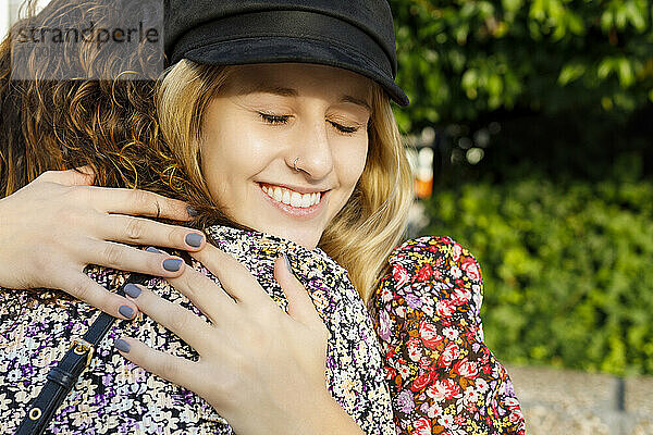 Blonde Frau umarmt Freundin an einem sonnigen Tag