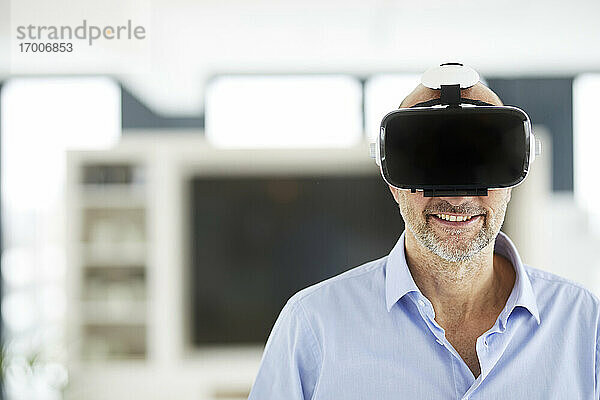 Geschäftsmann benutzt ein Virtual-Reality-Headset  während er zu Hause steht
