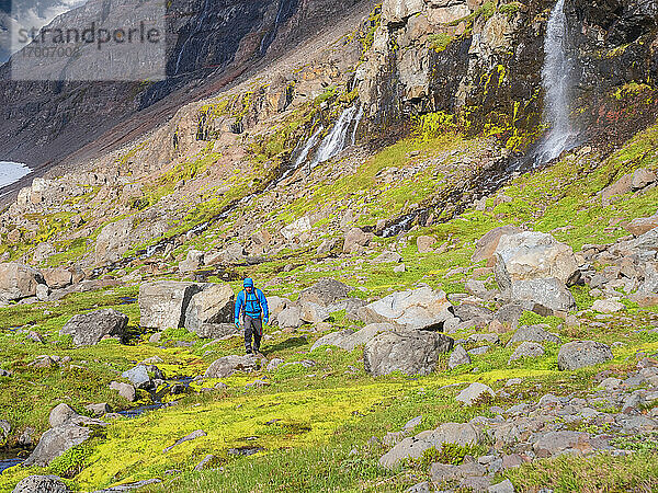 Männlicher Wanderer zwischen Felsbrocken in einem isländischen Tal