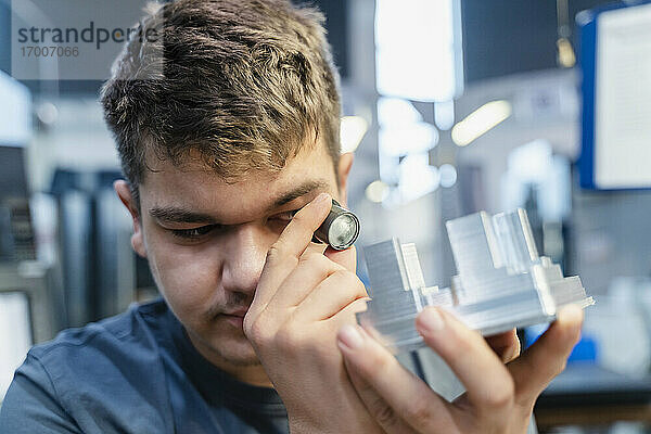 Ingenieur mit kleinem Mikroskop  der ein Modell untersucht  während er in der Industrie steht