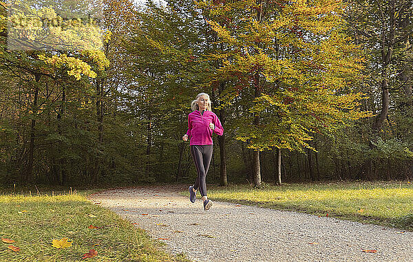 Frau joggt im Park gegen Bäume