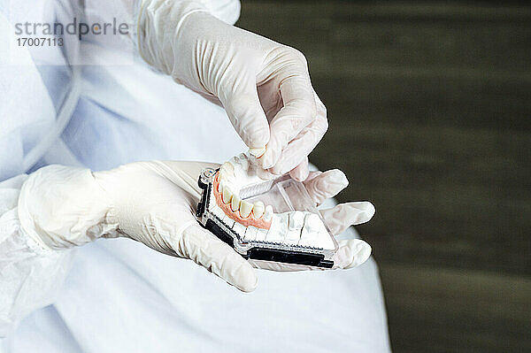 Zahnarzt mit Arbeitsschutzkleidung bei der Herstellung von Zahnersatz im Stehen in der Klinik