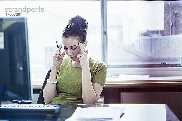 Frustrierte Unternehmerin mit dem Kopf in den Händen im Sitzungssaal ihres Büros