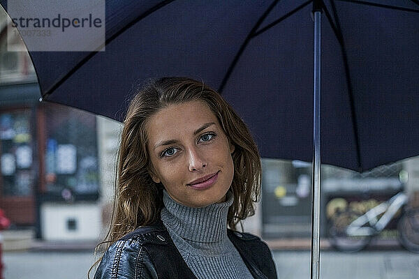 Geschäftsfrau unter Regenschirm auf der Straße während der Regenzeit