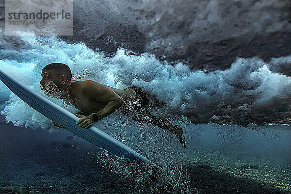 Männlicher Surfer  der mit einem Surfbrett ins Wasser taucht  auf den Malediven