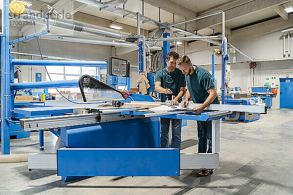 Zwei männliche Schreiner arbeiten zusammen in einer Produktionshalle