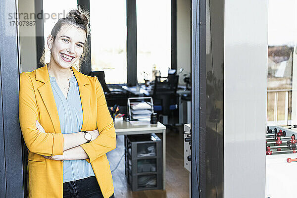 Junge Geschäftsfrau lächelt  während sie am Eingang eines Büros steht