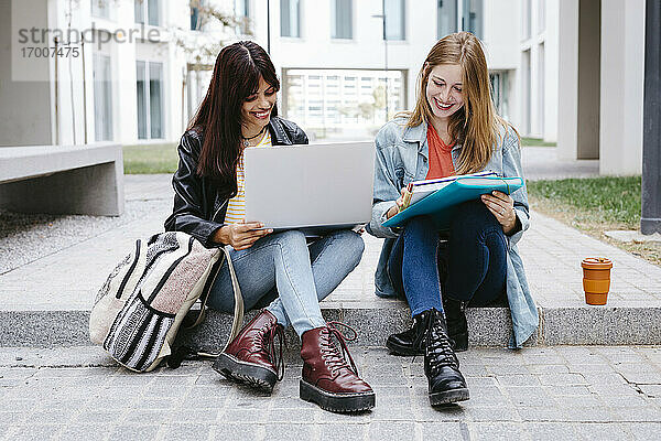Studentinnen studieren auf den Stufen eines Universitätsgeländes