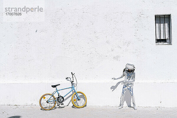 Junge im Astronautenkostüm steht mit seinem Fahrrad auf dem Gehweg in der Stadt